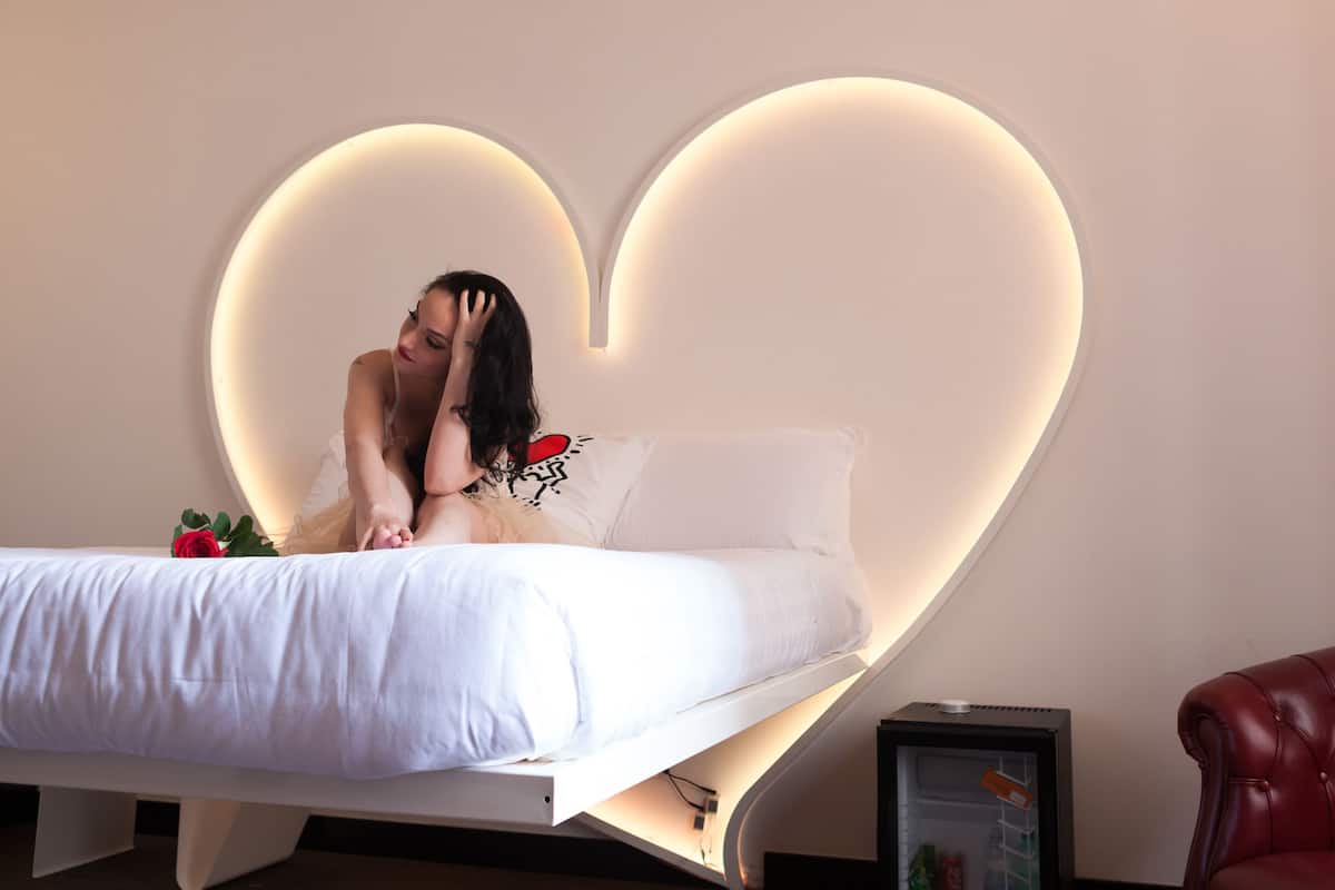 Ein Bett mit einer herzförmigen Lichtleiste darüber.