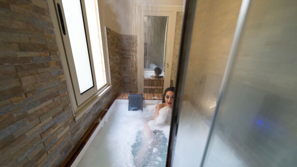 A spa room with a stone wall, a bathtub with bubbles, and a wooden door in the background. -  Gueshouse o Affitacamere Magenta Campo dei Fiori  (Rome)