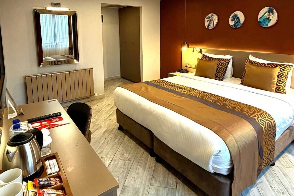 Una habitación de hotel con cama, mesita de noche y espejo.