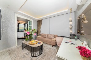 A modern living room with a sofa, a coffee table with snacks, a mirror with lights, and a view of a cityscape.
