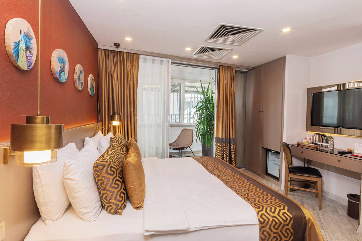 Una habitación de hotel con una cama, un escritorio, una silla, un televisor y una planta.