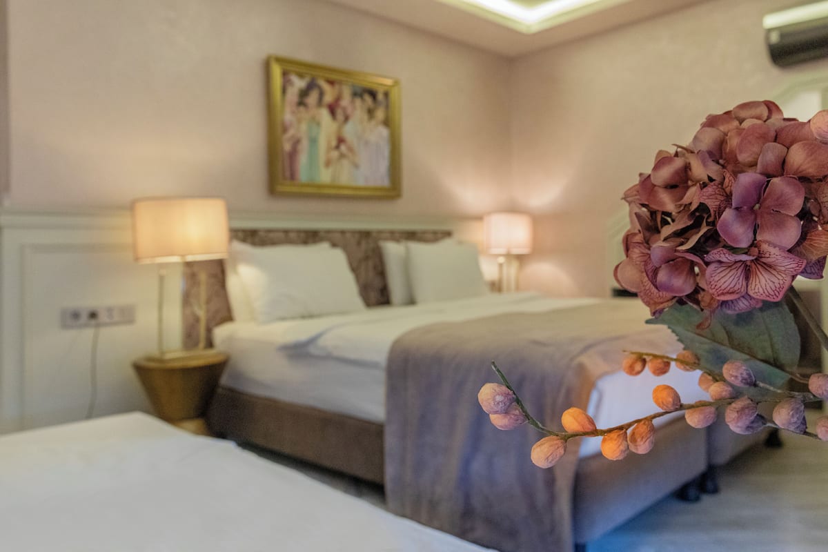 Una habitación de hotel con dos camas, un cuadro en la pared y un florero con flores.