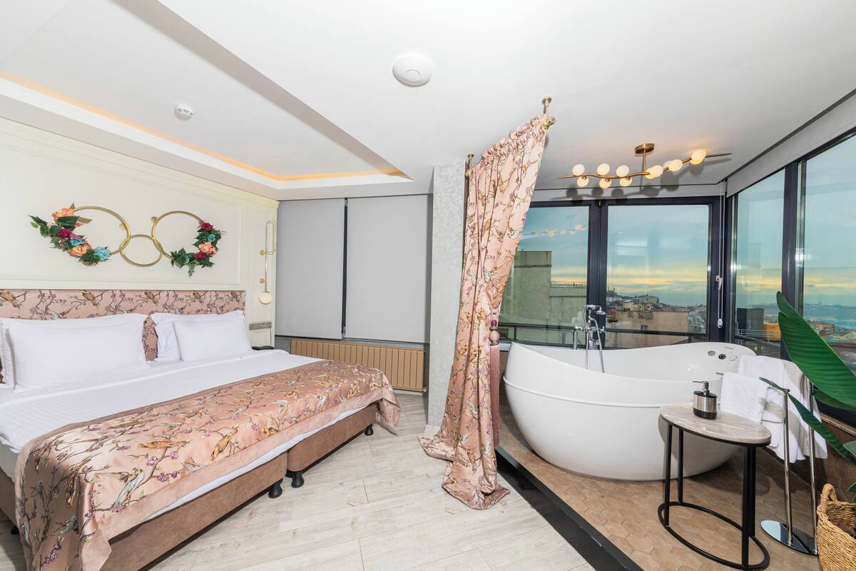 Un dormitorio con una cama grande, una bañera y vistas a la ciudad.