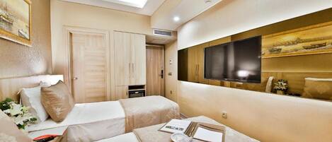 A hotel room with two beds, a TV, and a ceiling light.