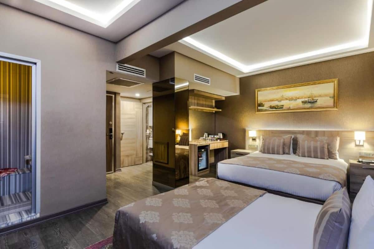 Una habitación de hotel con una cama grande, un escritorio y un cuadro en la pared.