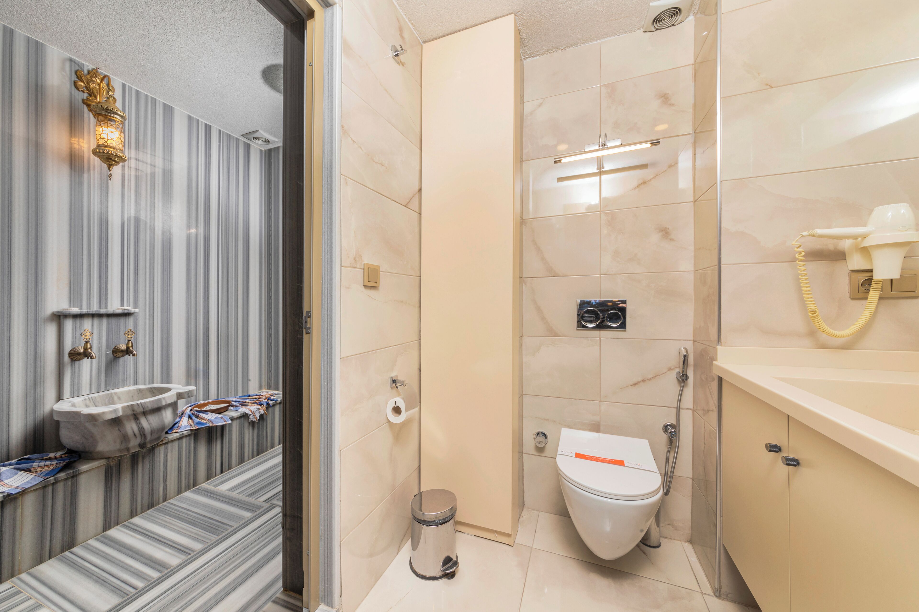 Een badkamer met een marmeren wastafel, toilet, douche en een handdoekrek.