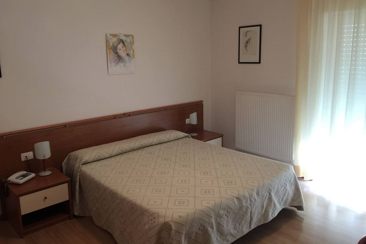 Ein Hotelzimmer mit einem Bett, einem Nachttisch mit Lampe, einem Telefon und einem Heizkörper.