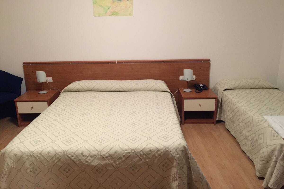Ein Hotelzimmer mit einem Doppelbett, zwei Nachttischen, einer Lampe und einem Bild an der Wand.