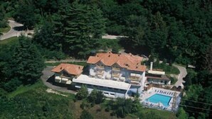 An aerial view of a large, multi-story house with a swimming pool, surrounded by dense greenery. - Hotel Ristorante Scaranò (Levico Terme)