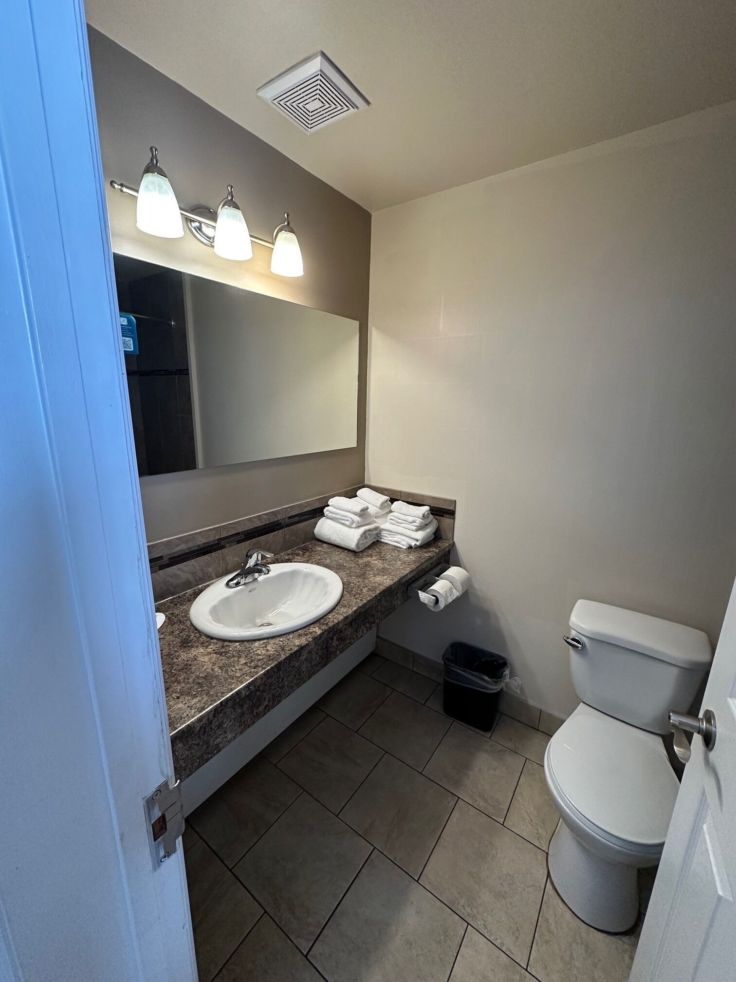 Een badkamer met een wastafel, spiegel, handdoekhouder en toilet.