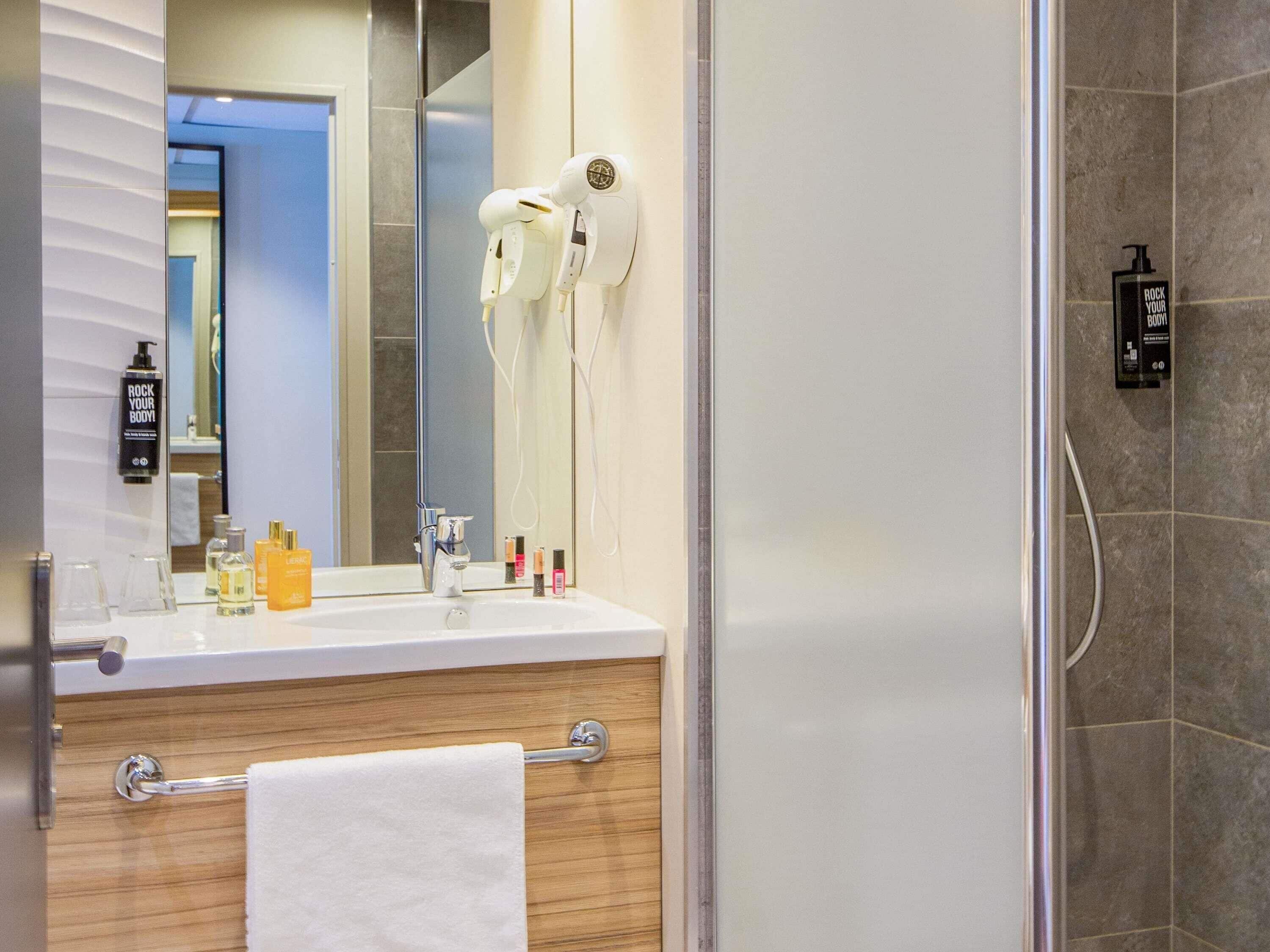 A bathroom with a mirror, hairdryer, and toiletries.