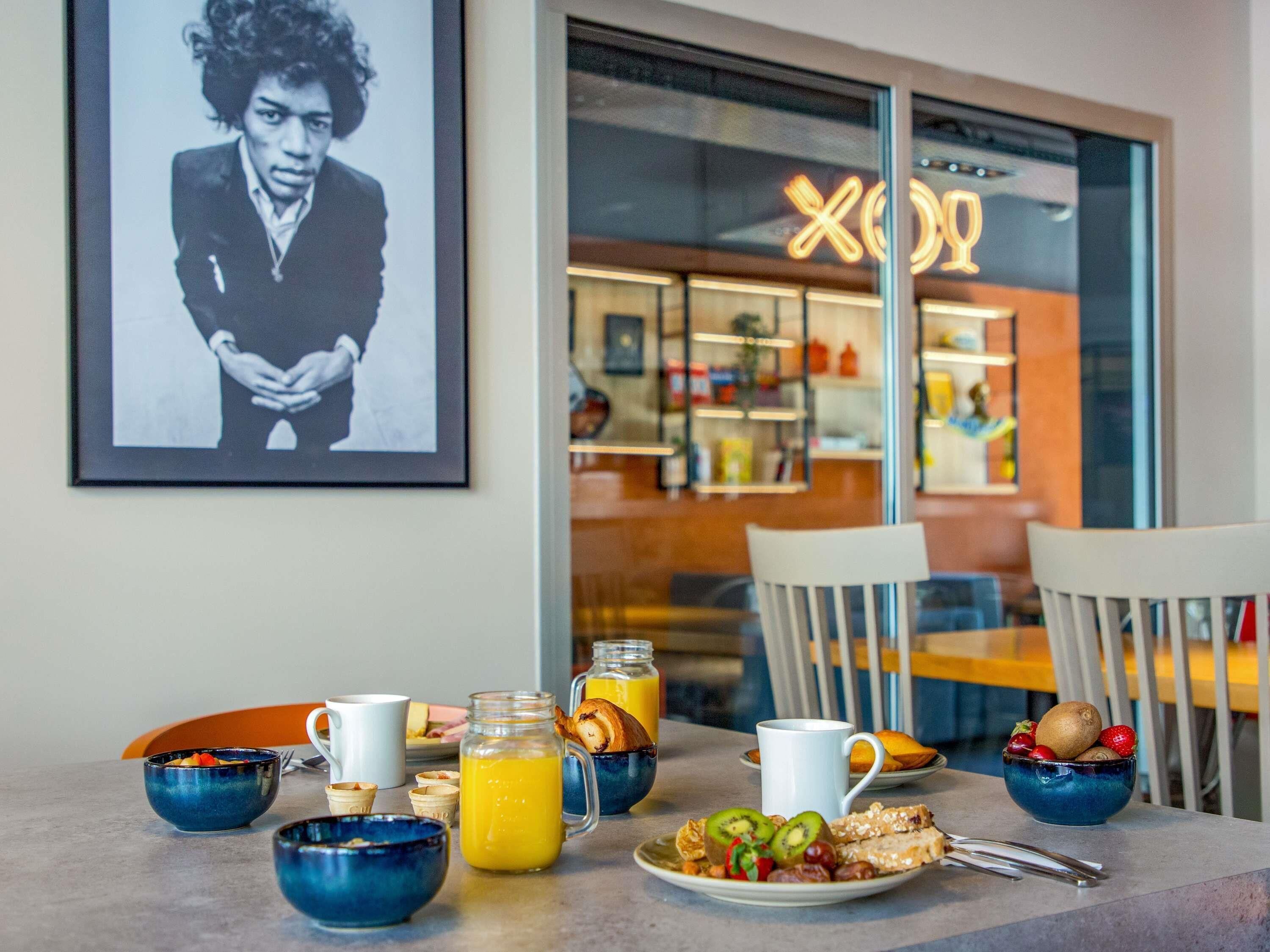 Una mesa de desayuno con diversos alimentos y un cuadro en la pared.