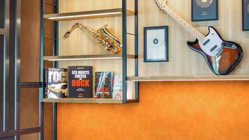Une pièce avec un mur en bois, un saxophone, une guitare, des livres encadrés et une chaise.