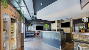 Un hall d’hôtel moderne comprenant un comptoir d’accueil, un espace salon et un présentoir réfrigéré.