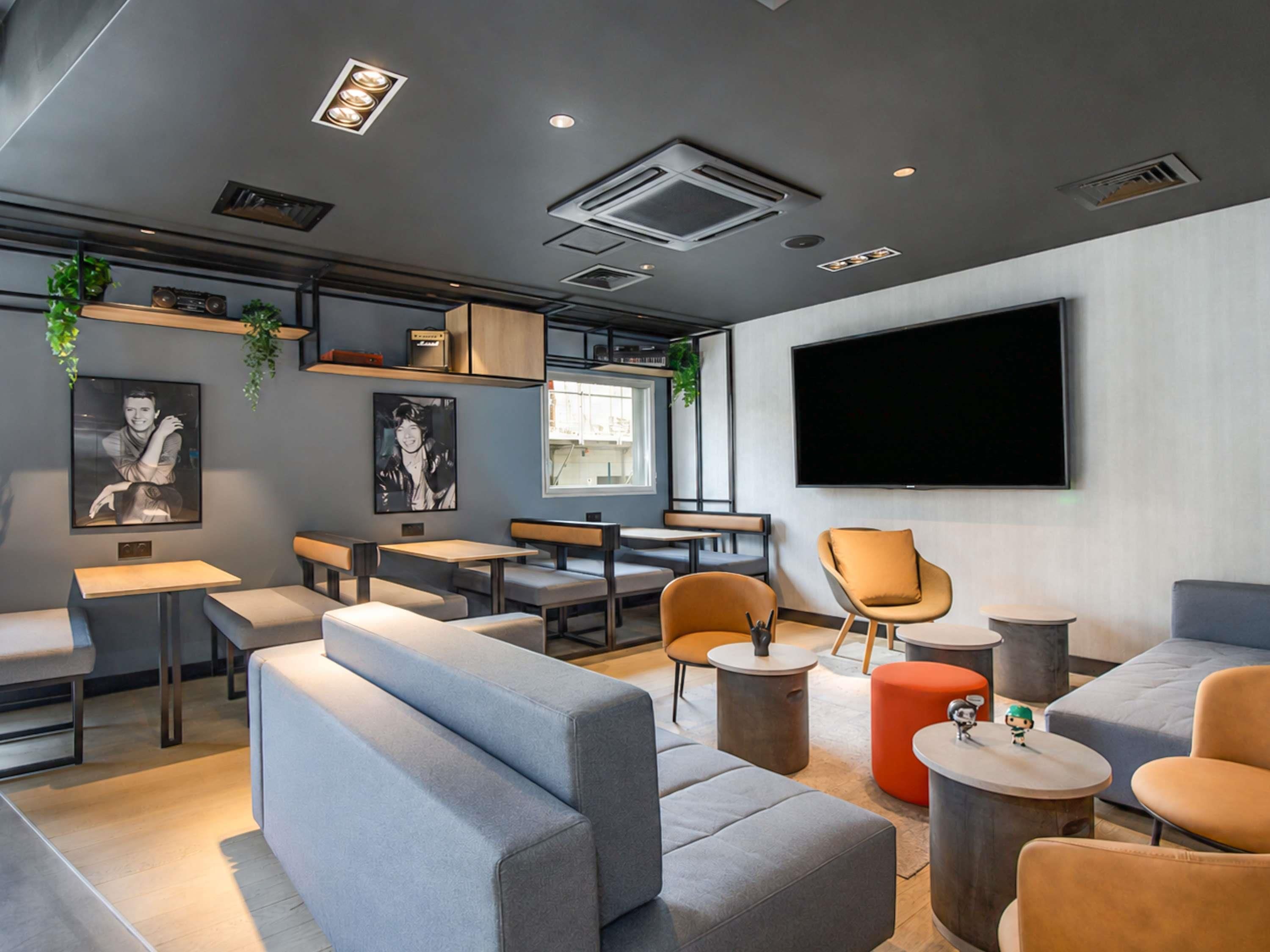 A modern lounge area with seating arrangements, a flat-screen TV, and a window providing natural light.