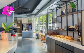 Un caffè moderno con un bancone centrale, area con posti a sedere e ampie finestre.