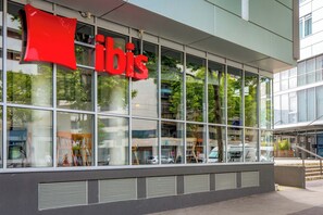 Un edificio moderno con ampie vetrate e un evidente cartello rosso con la scritta 'bis'.