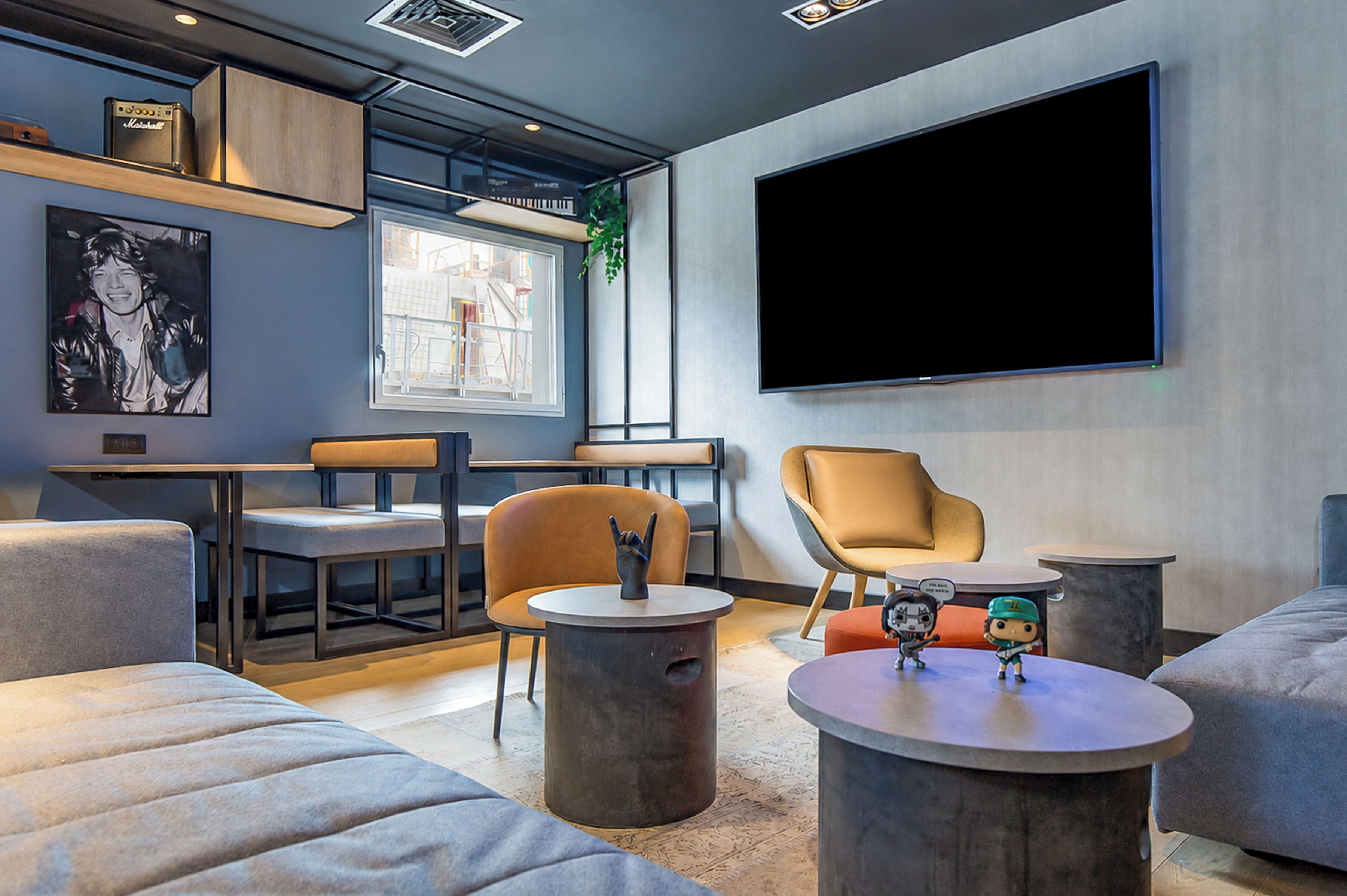 A modern lounge area with seating, a large flat-screen TV, and a window with a view.
