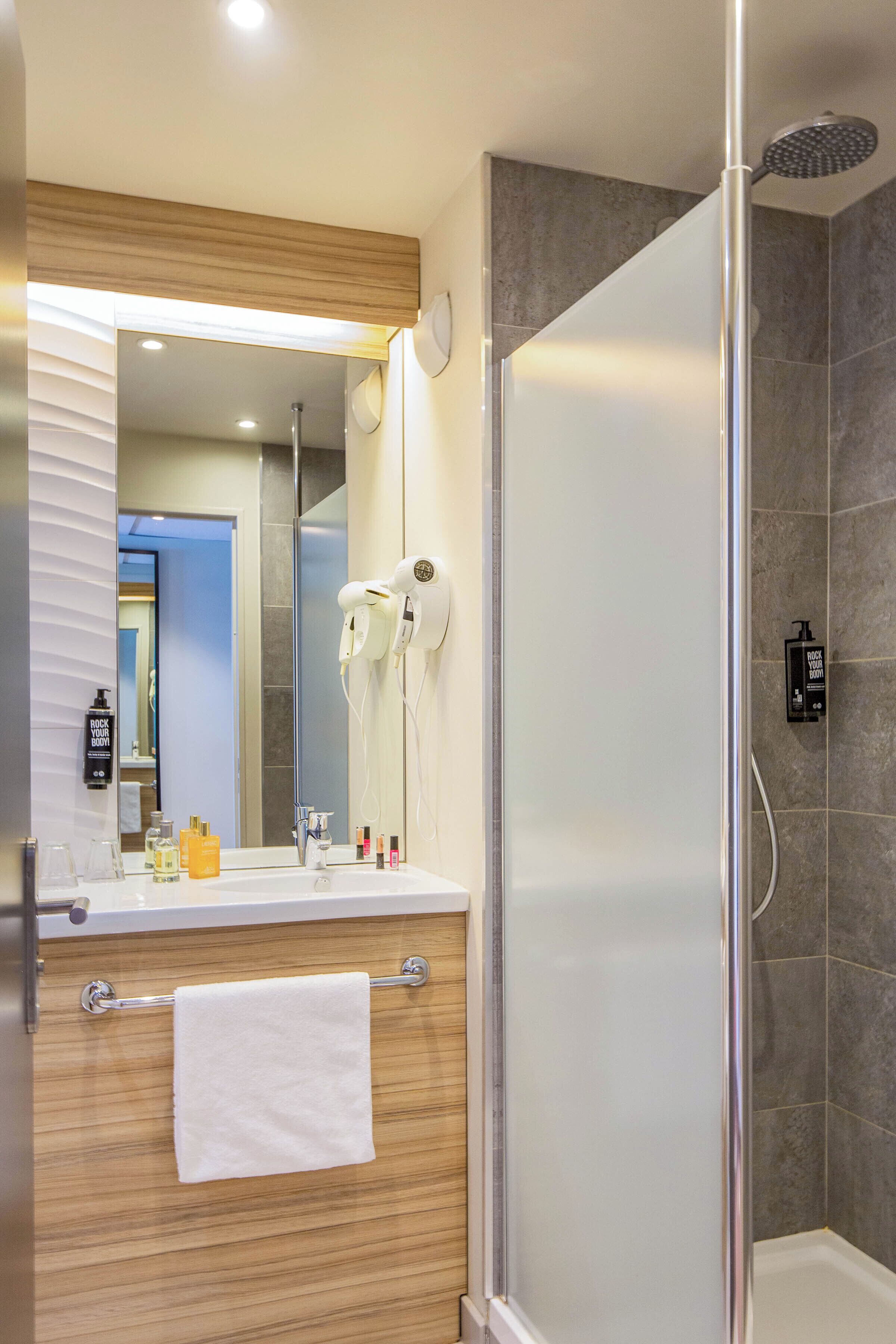 Une salle de bain moderne avec une douche à parois de verre, un meuble-lavabo avec une serviette et un miroir.