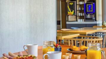 A breakfast table with a plate of food, a coffee cup, and a glass of orange juice.