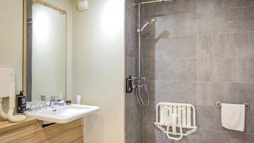 Une salle de bain équipée d’un lavabo, d’un miroir, d’une douche et d’un porte-serviettes.