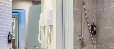 A modern bathroom with a glass shower enclosure, a bathtub, a vanity with a towel rack, and a mirror.