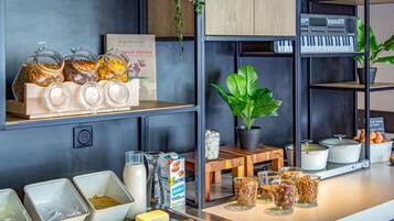 Una barra de desayuno con tarros de granola, una planta en maceta y un cartel con un nombre.