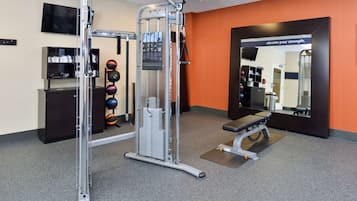 A gym with a squat rack, bench, and various weights.