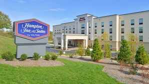 A Hampton Inn & Suites by Hilton building with a large sign, multiple windows, and a landscaped area with trees and shrubs. - Hampton Inn & Suites California University-Pittsburgh (Coal Center)