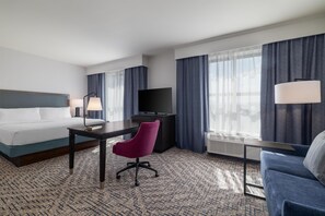 A hotel room with a bed, desk, chair, TV, and large windows with curtains. - Hampton Inn & Suites Roanoke-Downtown (Roanoke)