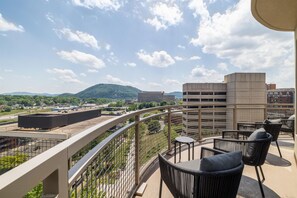 A balcony with outdoor furniture, a view of a parking garage, and distant buildings. - Hampton Inn & Suites Roanoke-Downtown (Roanoke)