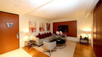 A modern living room with a sofa, armchairs, a coffee table, and a TV.