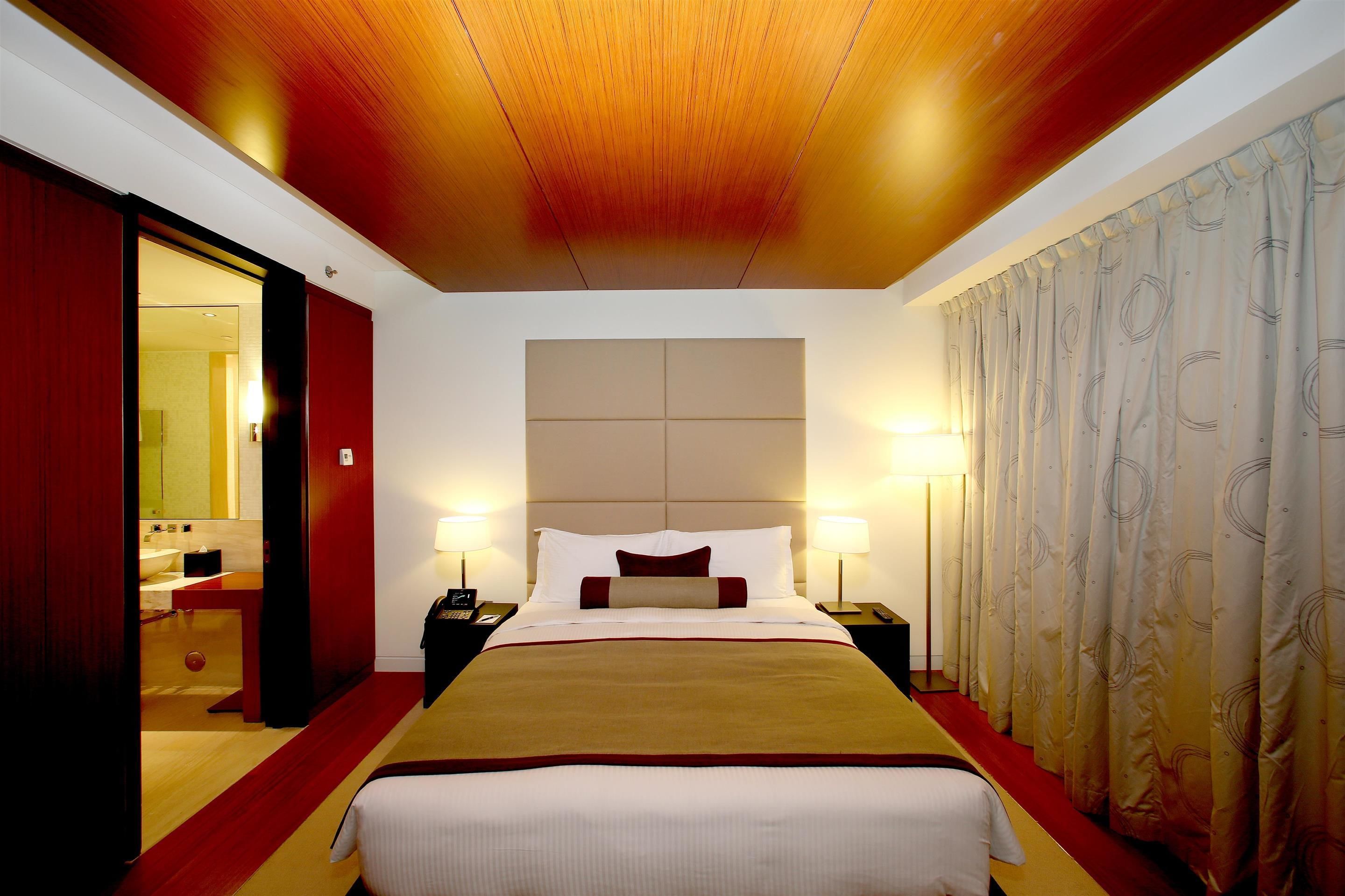 A hotel room with a large bed, wooden ceiling, and a red carpet.