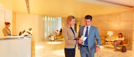 Una hall d'albergo con reception, aree salotto e un design moderno.