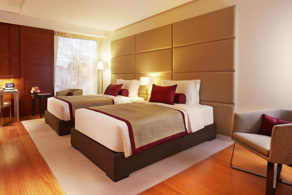A hotel room with two beds, a desk, and a chair.
