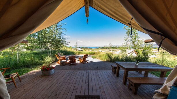 A wooden deck with outdoor seating, a table, and a view of the landscape. - Conestoga Ranch (Garden City)