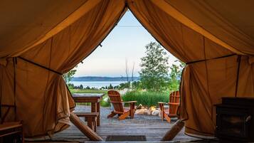 Relax in a cozy tent with a scenic view of the outdoors, featuring a fireplace and outdoor seating area.