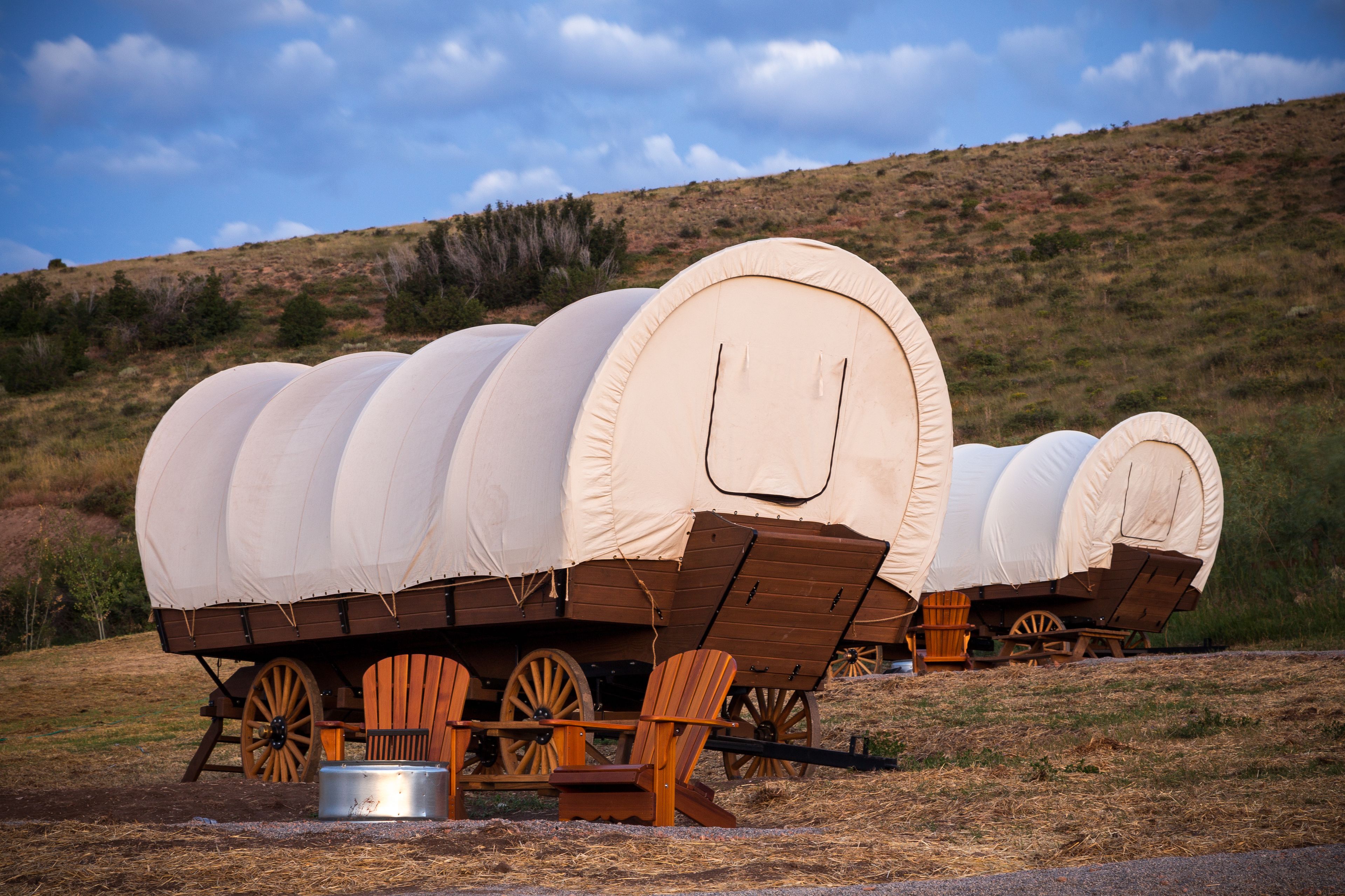A covered wagon with wooden wheels and a metal pot.