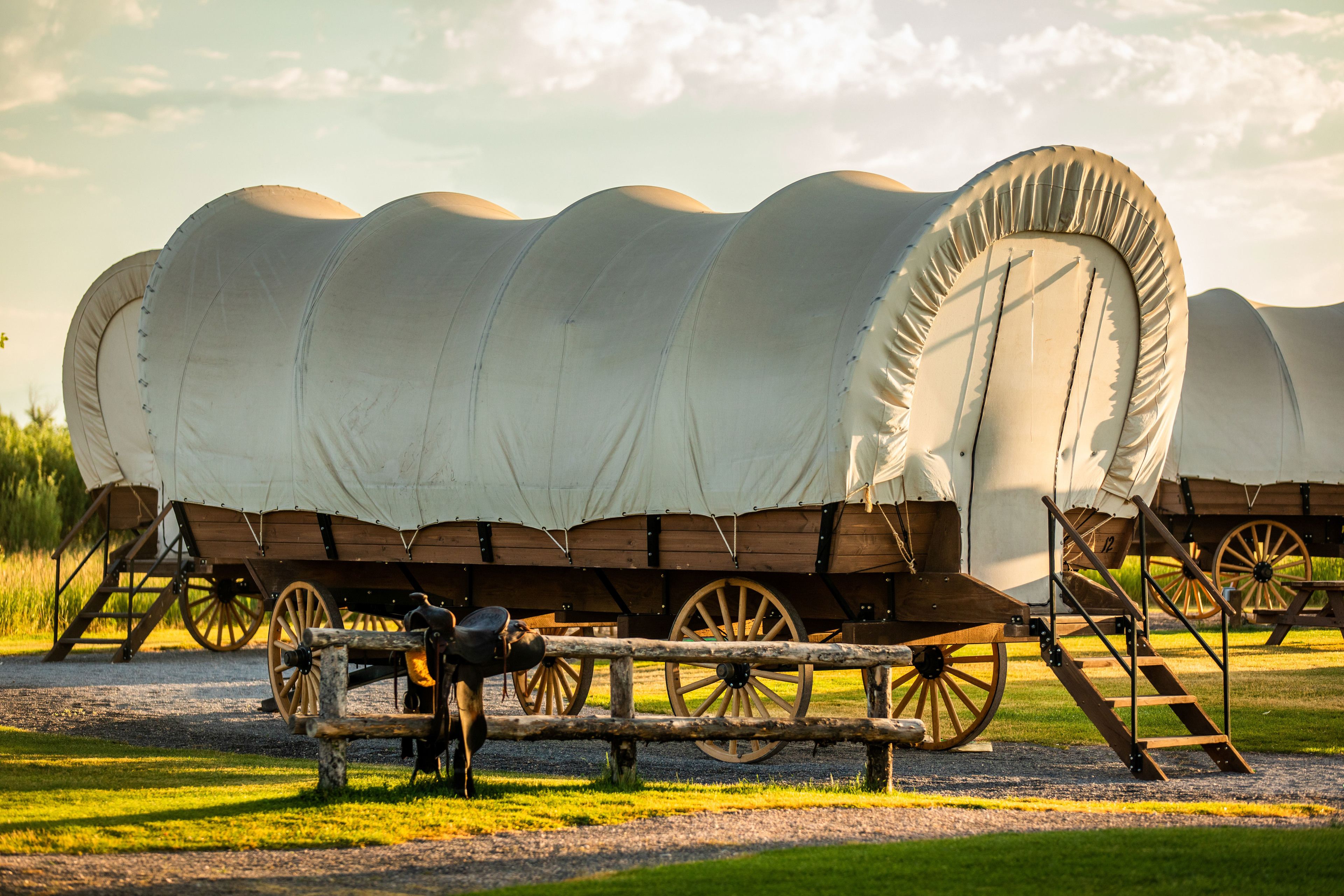 A covered wagon with a large canvas canopy, wooden wheels, and a ladder.