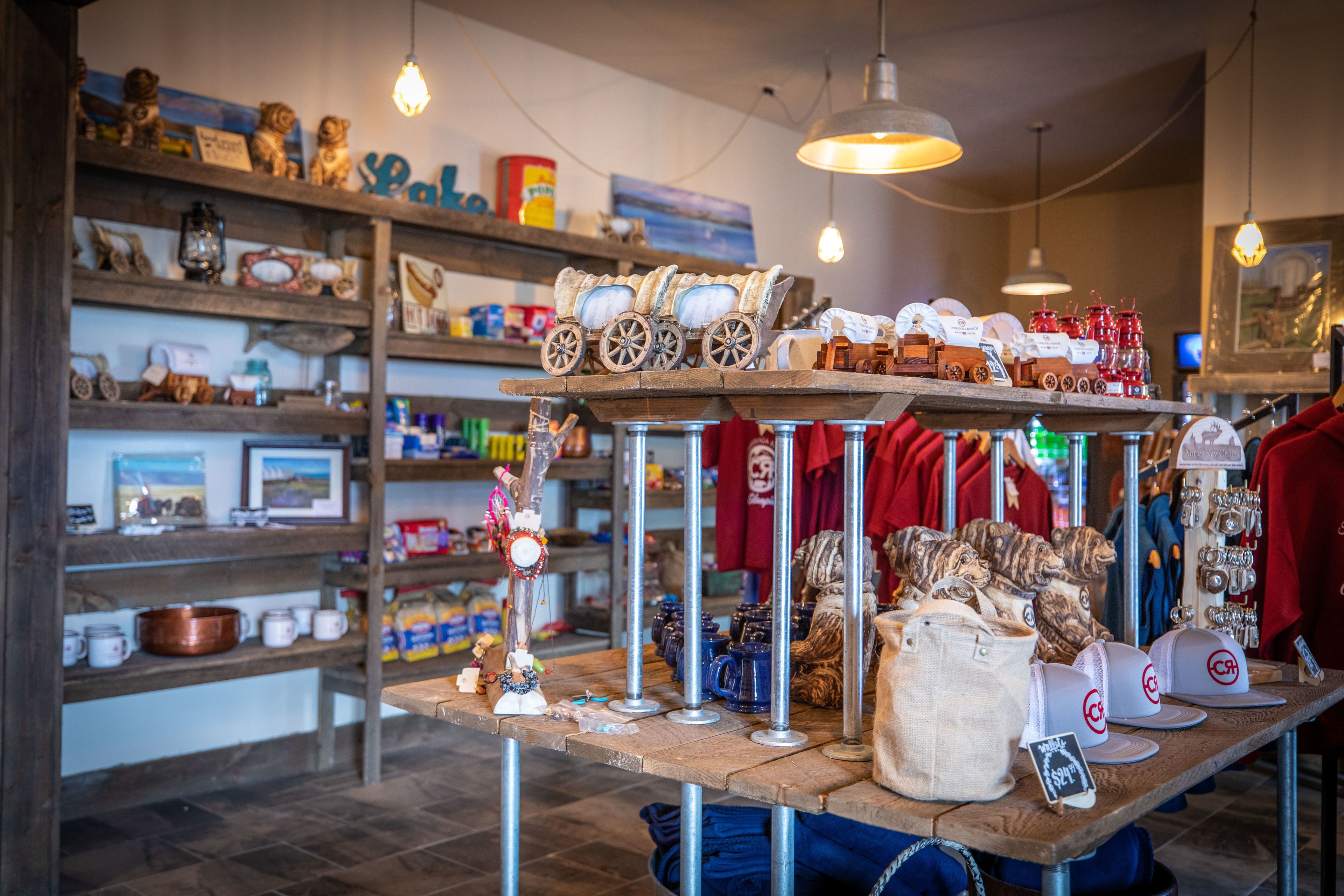Un magasin dont les étagères sont remplies de divers articles, une table de présentation où sont exposés des chapeaux et des sacs, et une pancarte indiquant une vente.