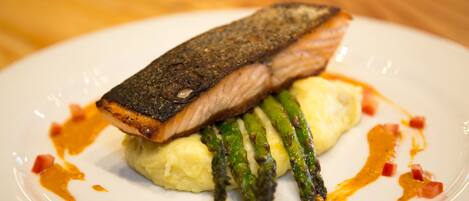 A plate with a piece of salmon, asparagus, and mashed potatoes.