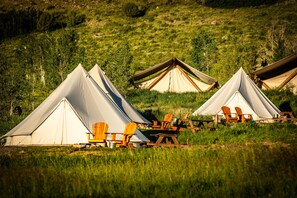 Guests can enjoy a peaceful campsite setup with a tent, chairs, and picnic table.