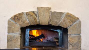 A rustic stone fireplace with a fire burning inside, a metal sign with Cyrillic letters above it, and a stone archway framing the fireplace.