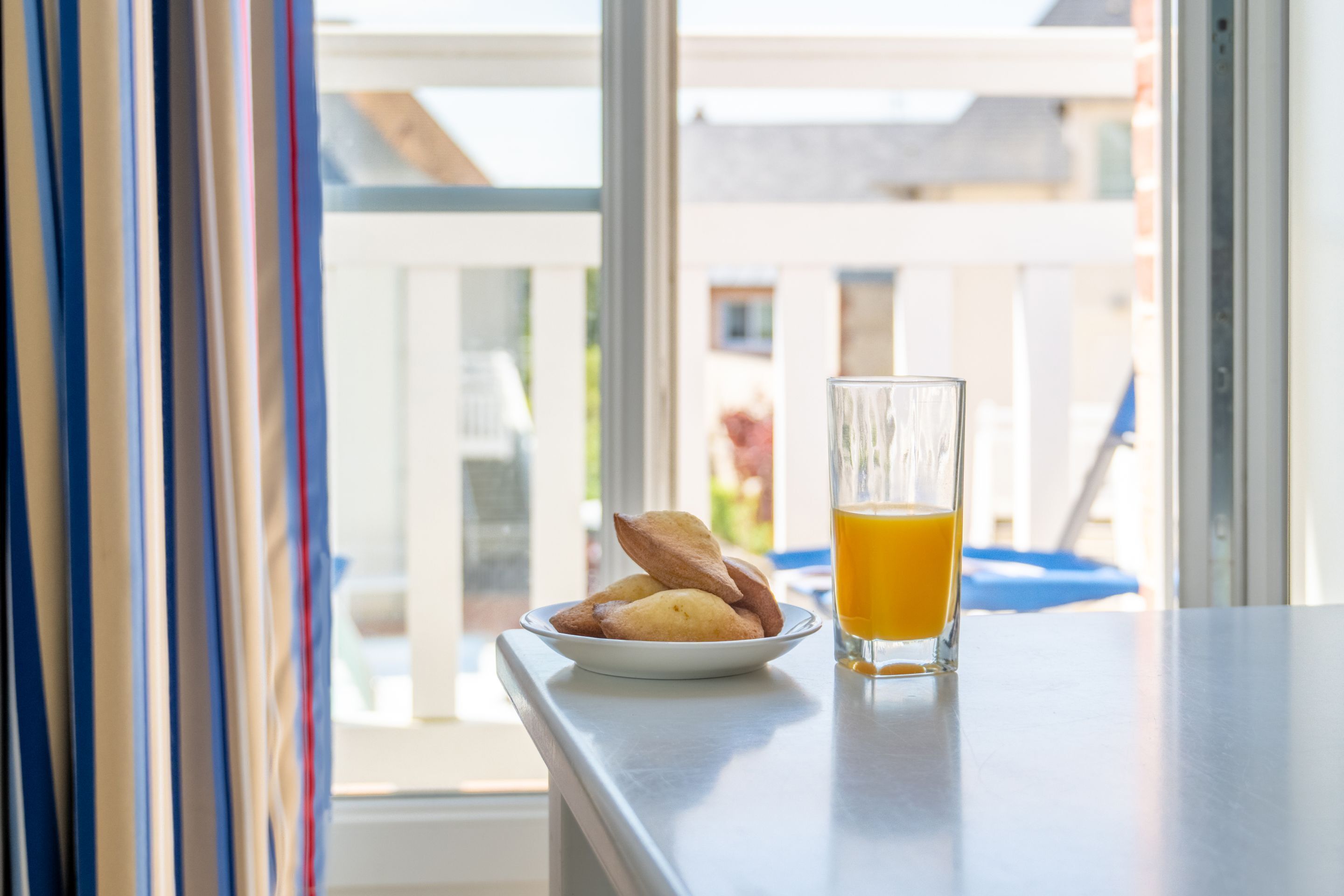 En morgenmadsopstilling med et bakværk og et glas appelsinjuice på en balkon.