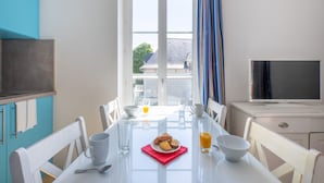 Comedor con una mesa dispuesta para el desayuno, incluyendo un plato de pastelería y un vaso de jugo de naranja.