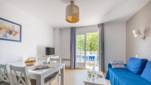Una habitación moderna con una mesa de comedor, un sofá, un televisor y una ventana con cortinas.