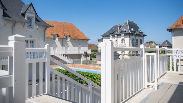 Zona residencial cerrada con piscina, cercas blancas y casas de diferentes estilos de techo.