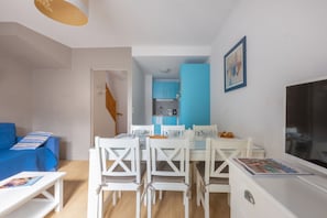 A compact living space with a dining area, kitchenette, and a blue sofa.