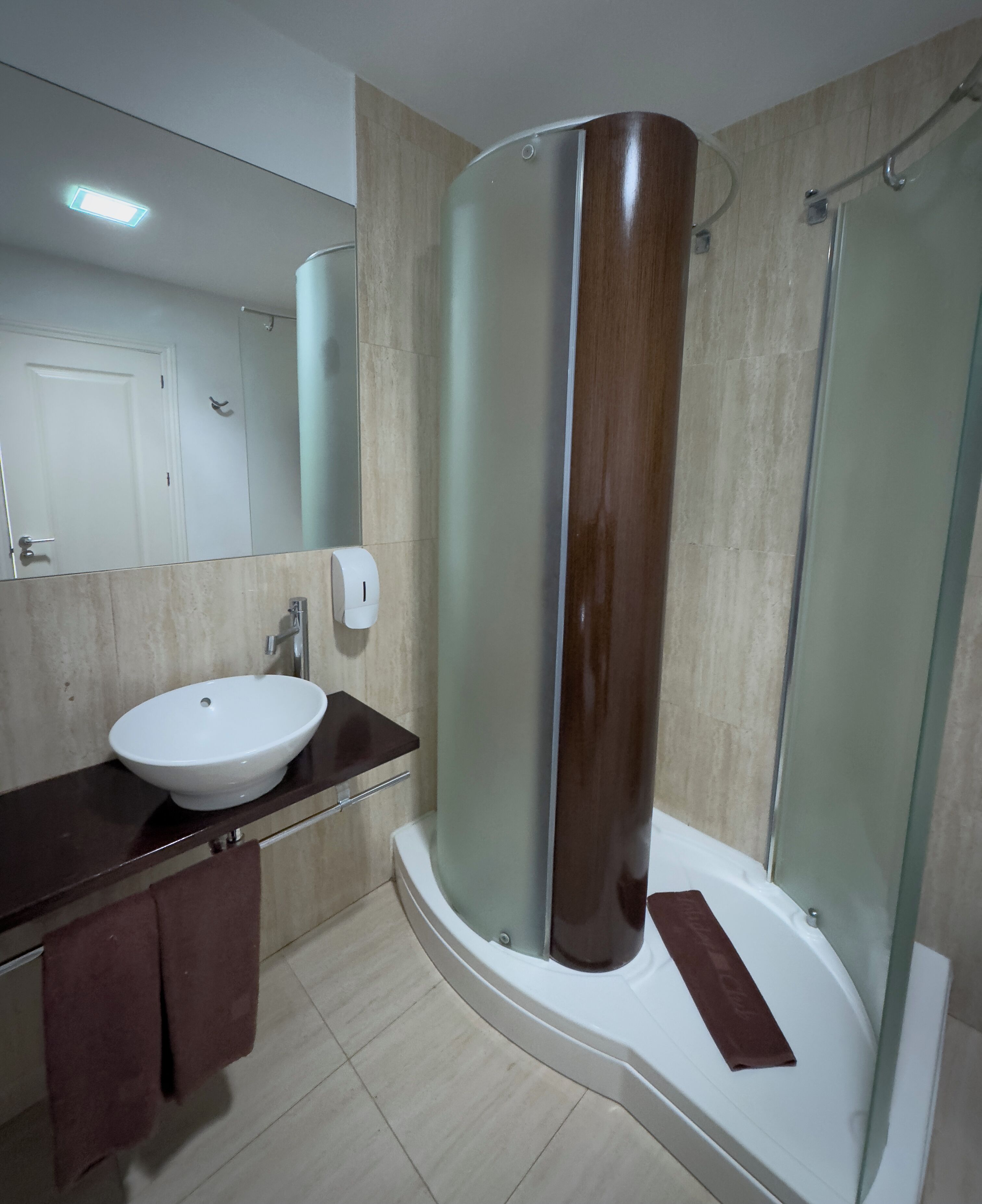 A modern bathroom with a white sink, a glass shower enclosure, and a mirror.