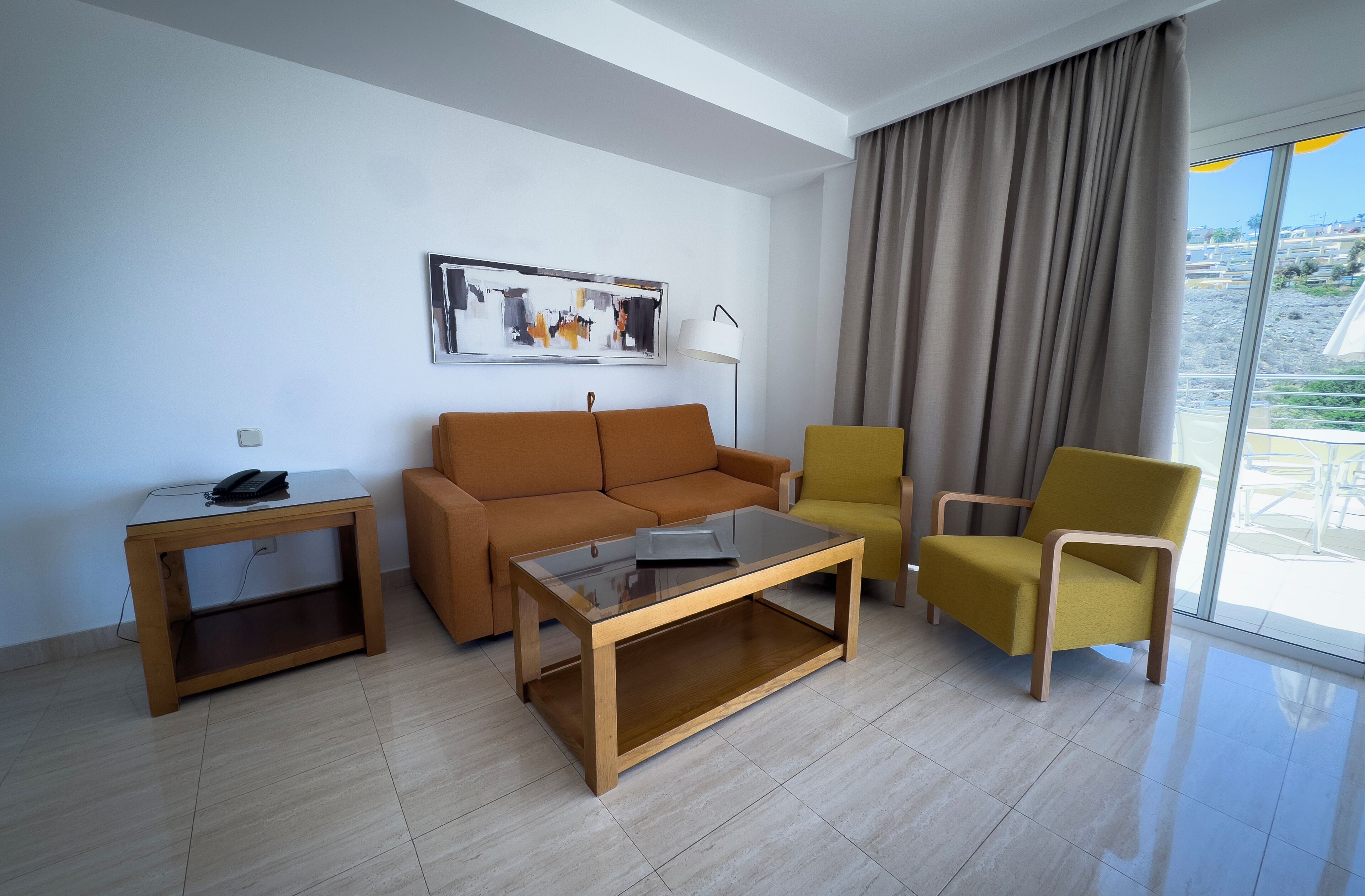 Un salon moderne comprenant un canapé, un fauteuil, une table basse et une table d’appoint avec une lampe.